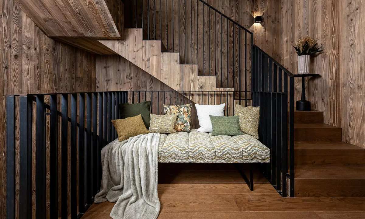 Gepolsterte Sitzbank mit Kissen unter einer Holztreppe